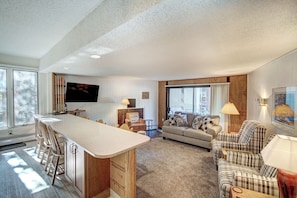 A spacious living area with a kitchen counter, a sofa, and a television.