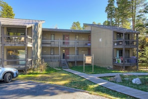 A multi-story building with balconies, a parking area, and a wooden deck. - Gold Camp II E87 Condo (Breckenridge)
