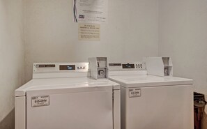 Deux lave-linge Maytag à usage commercial, dotés d’écrans numériques, d’une étiquette d’entretien et d’un panneau d’instructions fixé au mur.