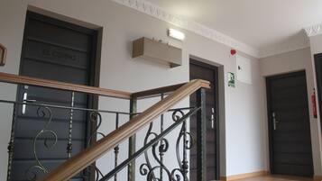 A staircase with a wooden handrail and metal balusters, leading to a dark door labeled "EL CERRO".