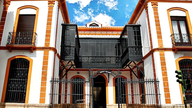 Un edificio de arquitectura de dos pisos, con ventanas de arco y balcones con barandillas de hierro forjado.
