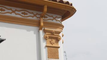 Esquina de un edificio con una columna decorativa y techo de tejas.