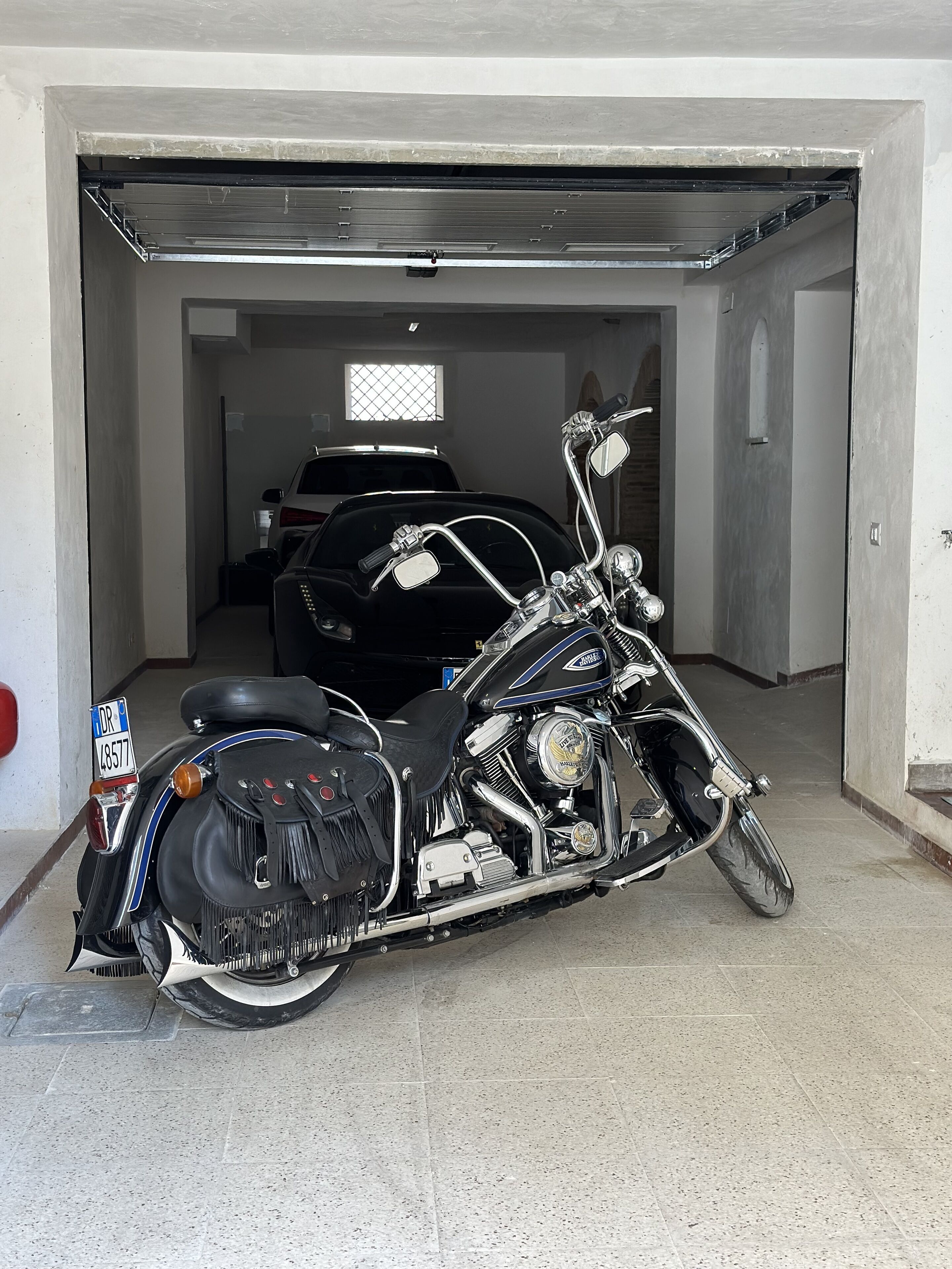 Una motocicleta estacionada dentro de un garaje, con un coche al fondo.