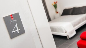 Habitación de hotel con una cama, una mesita pequeña y un cartel en la pared que indica el número 4.