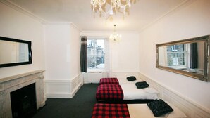 A hotel room with two beds, a fireplace, a large mirror, and a view of the city through a window. - Edinburgh Princes Street Top Floor Apt (Edinburgh)