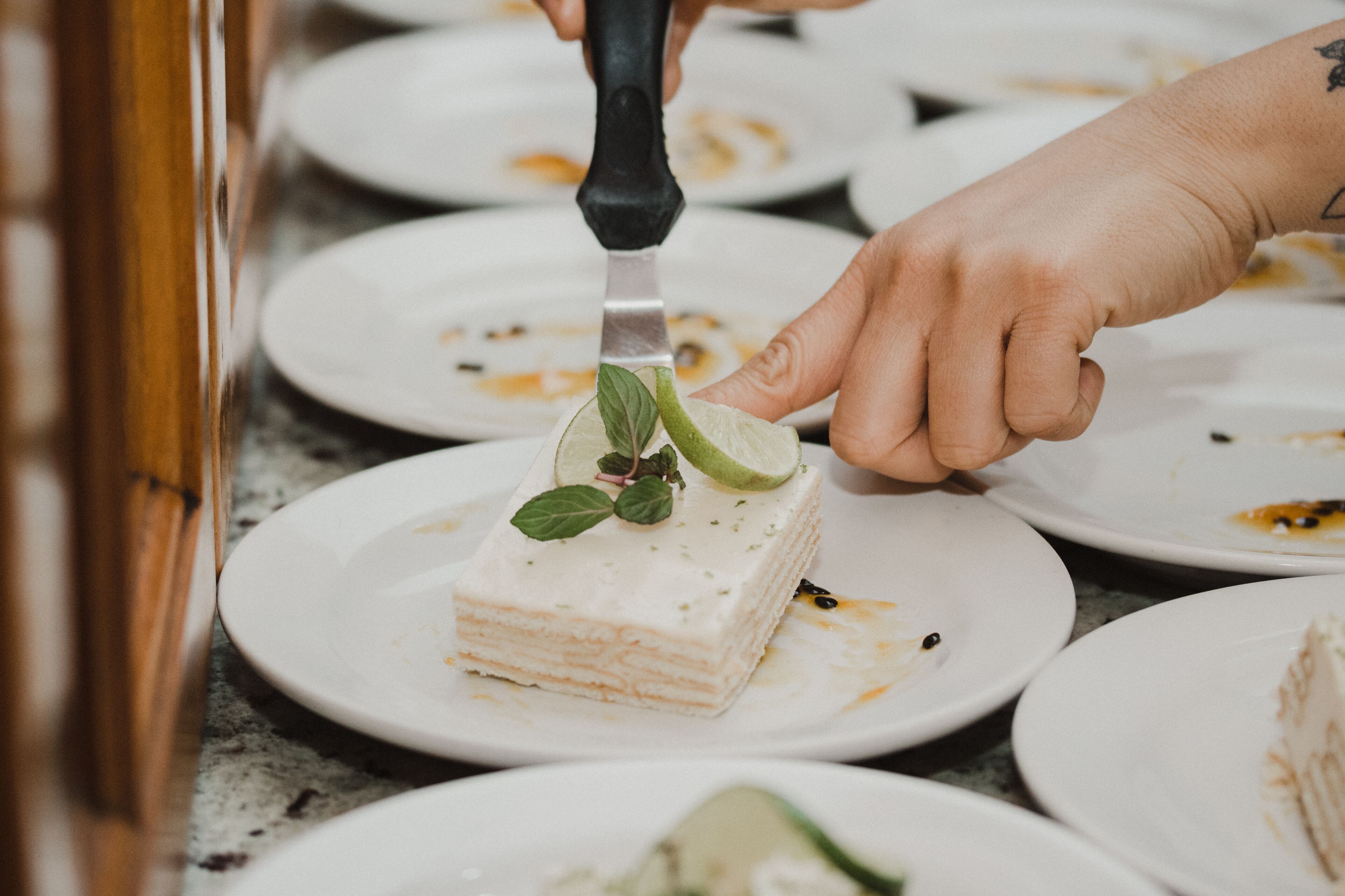 A person cutting a layered dessert with a knife.