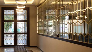A hallway with a bench, a geometric patterned wall, and a ceiling light fixture. - Casa Basalto (Pachuca)