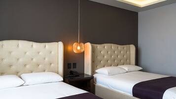 Una habitación de hotel con dos camas, una mesita de noche y una lámpara colgante.