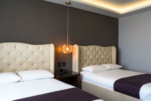 Una habitación de hotel con dos camas, una mesita de noche y una lámpara colgante.