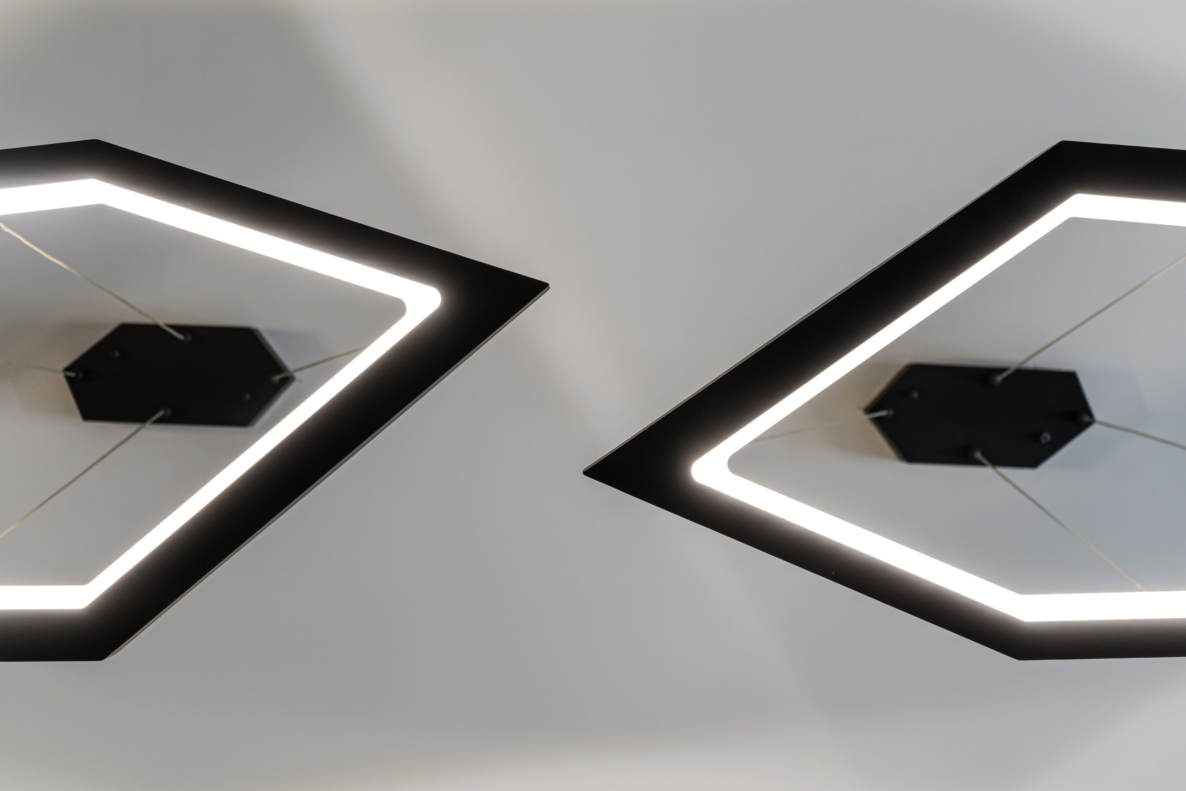Dos lámparas geométricas con diseño hexagonal, instaladas en una pared lisa.