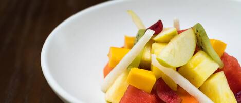 A white bowl filled with a variety of fruits including watermelon, pineapple, and mango.
