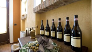 A table with six wine bottles and a plate with grapes and decorative leaves. - Agriturismo Cascina Monchiero (Bra)