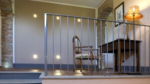 A staircase with a metal railing, a vintage chair, and a small table with a doll and toy vehicles. - Agriturismo Cascina Monchiero (Bra)