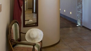 A room with a wooden chair, a white hat, and a red curtain. - Agriturismo Cascina Monchiero (Bra)
