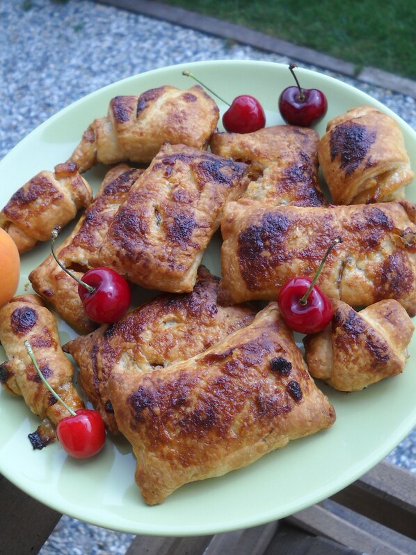 A plate of golden-brown pastries with cherries on a light green plate. - Agriturismo Cascina Monchiero (Bra)