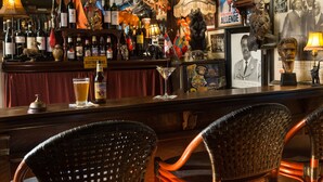Un espace bar avec des fauteuils en osier, des bouteilles d’alcool et diverses décorations.