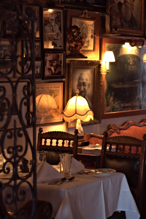 A dining area with a table set for two, surrounded by framed pictures and a lamp. - Pentagoet Inn (Castine)