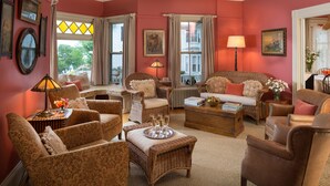 Un salon chaleureux, avec des meubles en osier, une table basse sur laquelle est posée une barquette de verres et une cheminée.