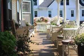 A wooden deck with wicker furniture and a white picket fence. - Pentagoet Inn (Castine)