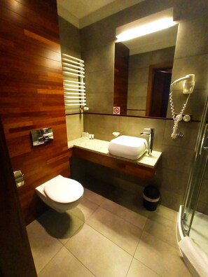 A modern bathroom with a wooden vanity, a toilet, a sink, and a shower.