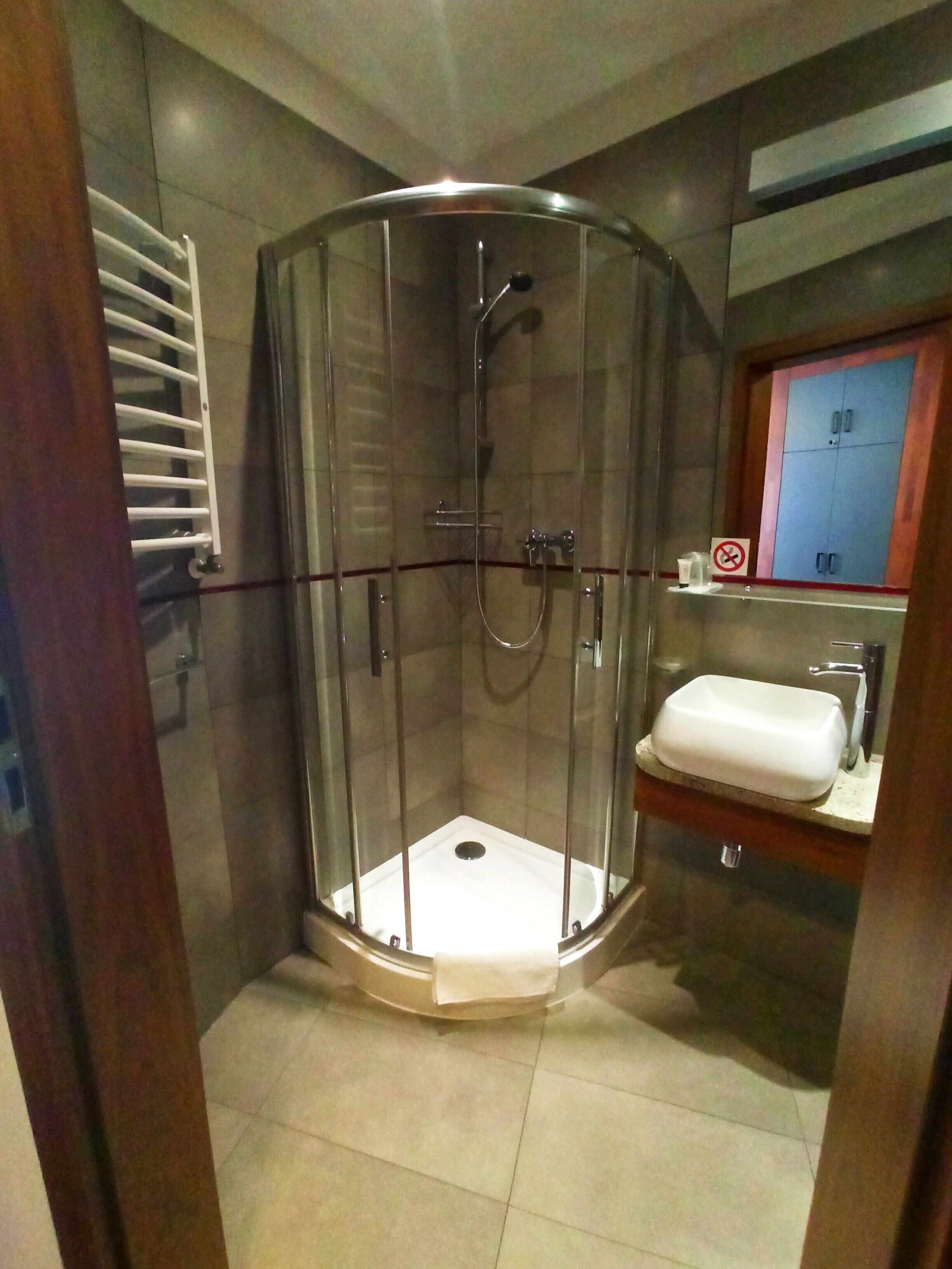 A glass-enclosed shower with a white sink and a wooden cabinet.