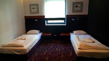 Habitació d'hotel amb dos llits individuals, una finestra gran i una televisió plana.
