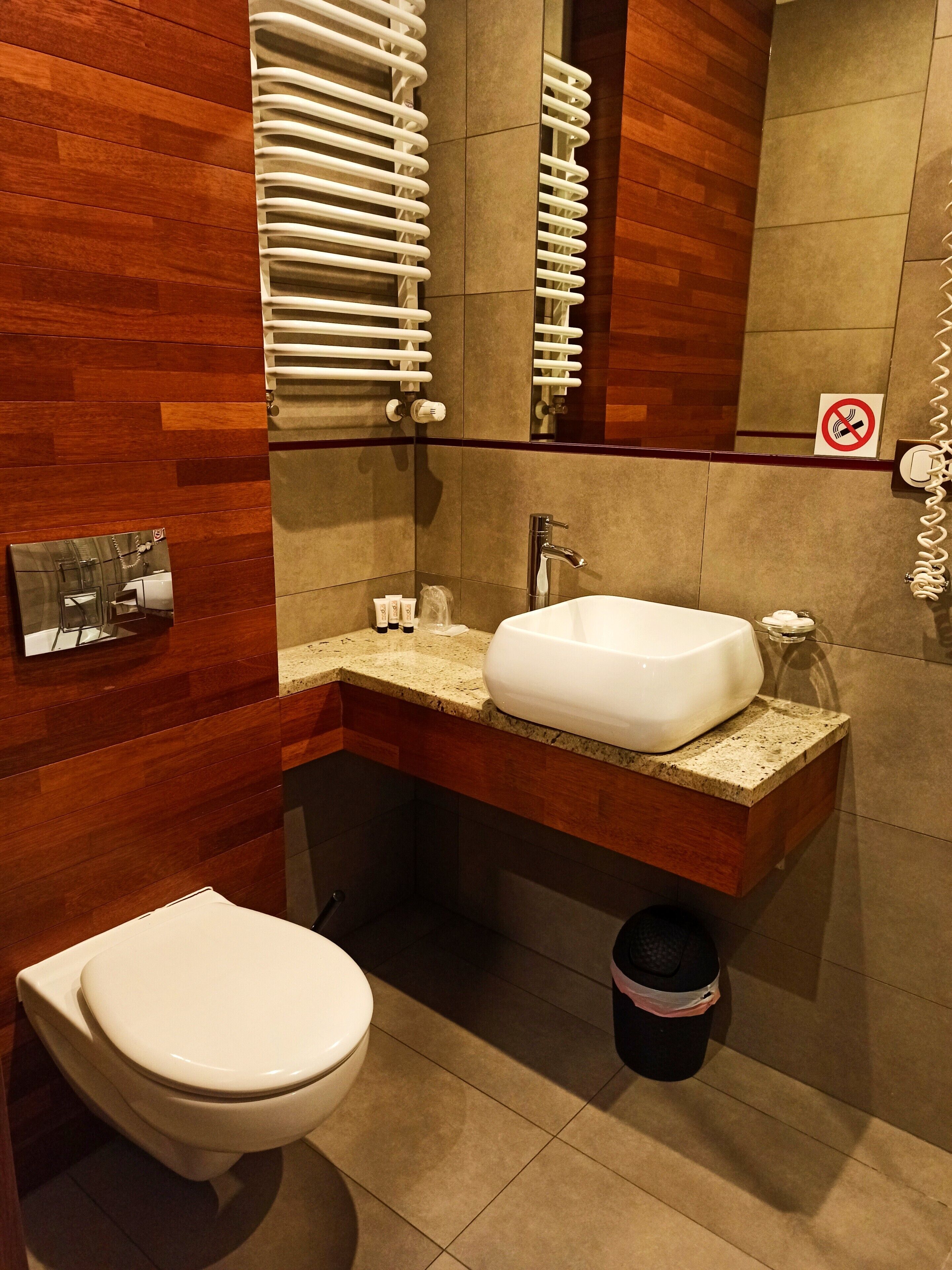 A modern bathroom with a wooden vanity, a white sink, and a toilet.