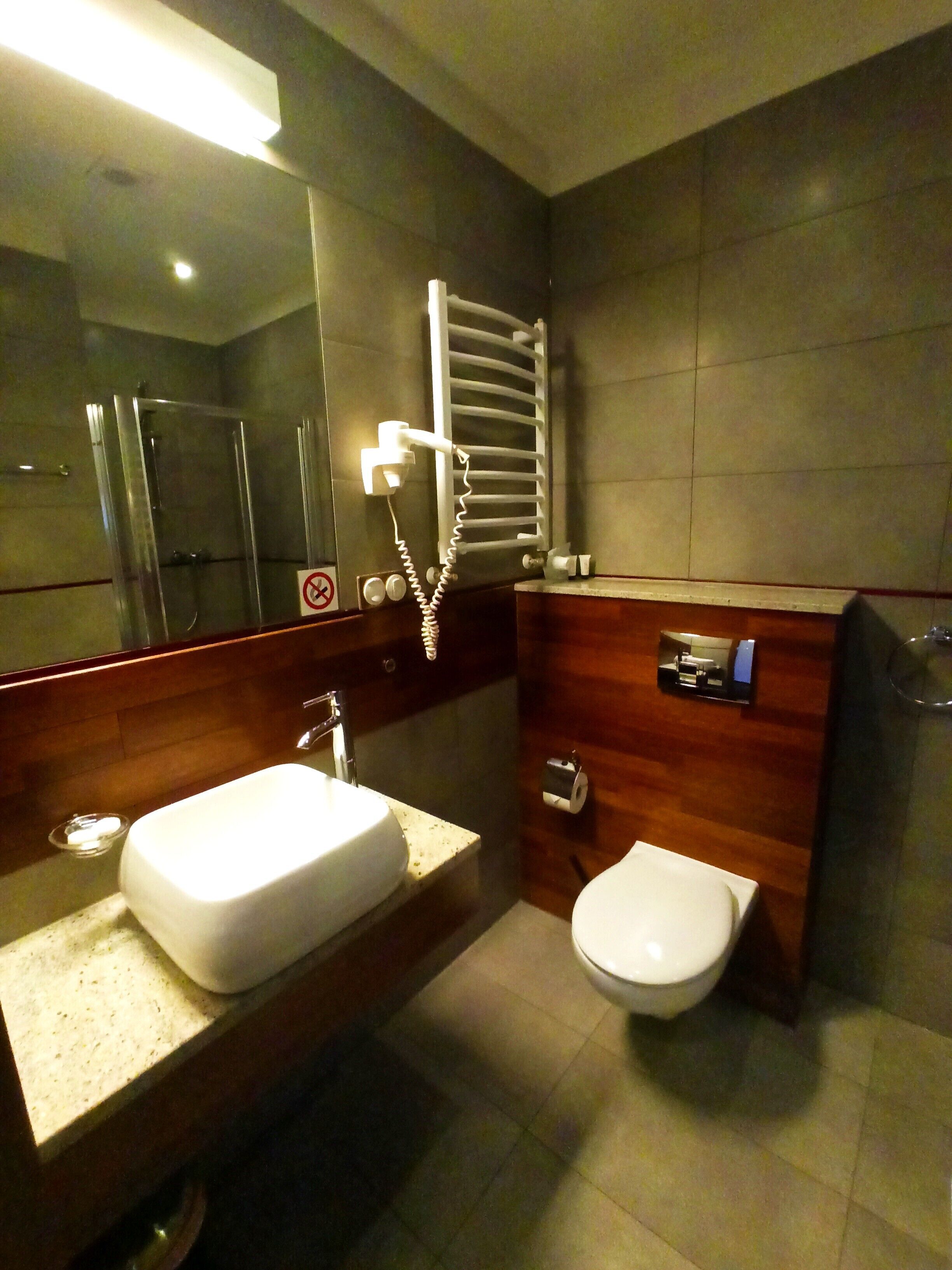 Une salle de bain moderne avec un grand miroir, un lavabo, des toilettes et une douche.