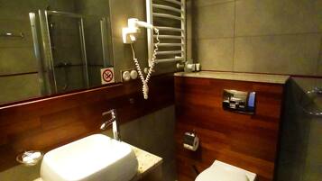 Une salle de bain moderne avec un grand miroir, un lavabo, des toilettes et une douche.