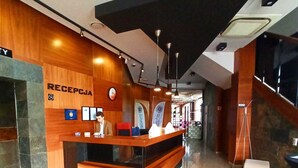 Zona de recepción con mostrador de madera, un reloj y un letrero que dice "RECEPTION".