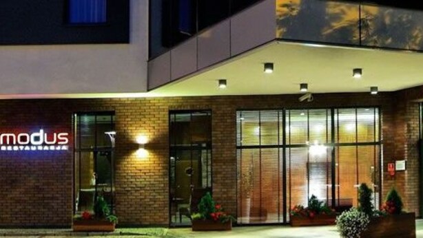 Un hotel moderno con un llamativo letrero 'modus', ventanas amplias y una entrada bien iluminada.