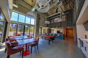 A spacious indoor area with a pool table, red chairs, and a bar area. - Domicile Suites at Chroma SLU (Seattle)
