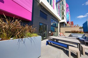 A modern building with a flat roof, large windows, and a seating area with benches and tables. - Domicile Suites at Chroma SLU (Seattle)