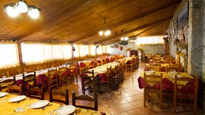 A spacious dining hall with multiple tables and chairs, wooden ceiling, and stone walls. - Agriturismo Falode (Castello del Matese)