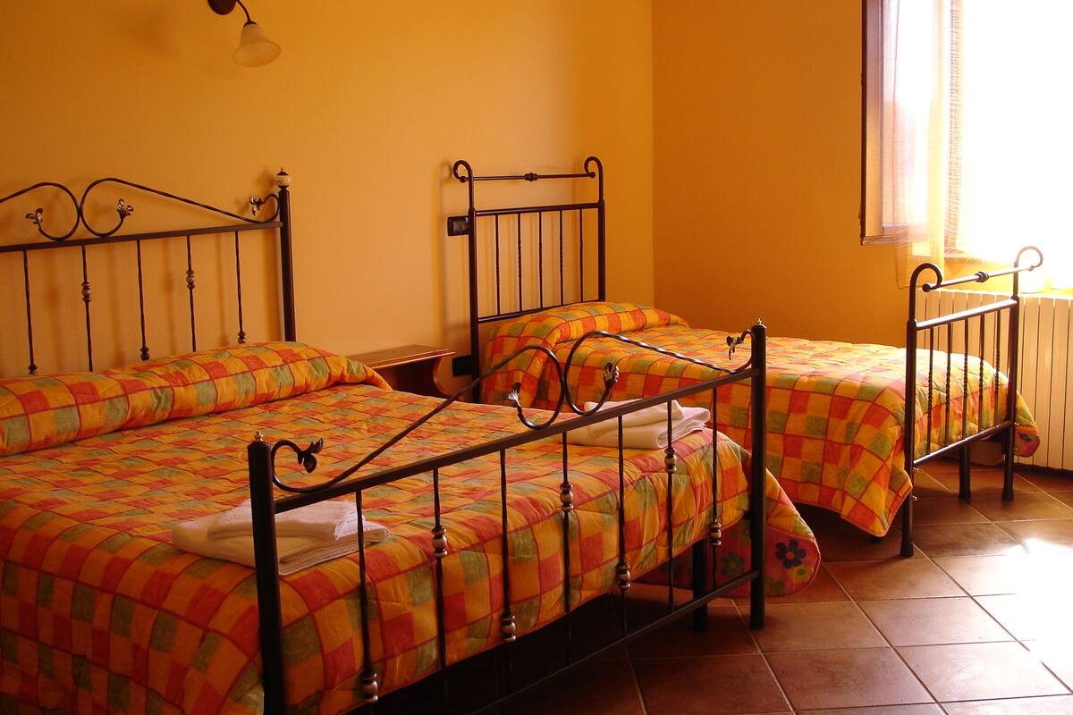 A room with two beds, each with a metal frame and colorful bedding.