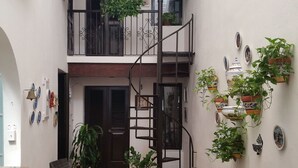 Un patio con muebles de mimbre, plantas en macetas y una escalera de caracol.