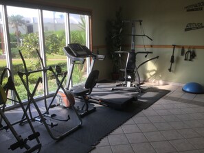 Un gimnasio con equipamiento de ejercicio, una cinta de correr y una pared con frases motivacionales.