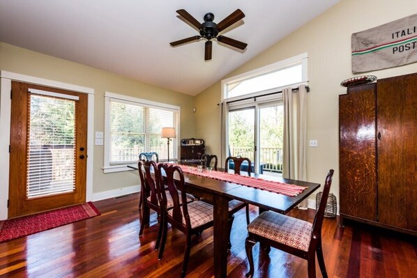 A dining area with a wooden table, chairs, a ceiling fan, and a view of the outdoors.