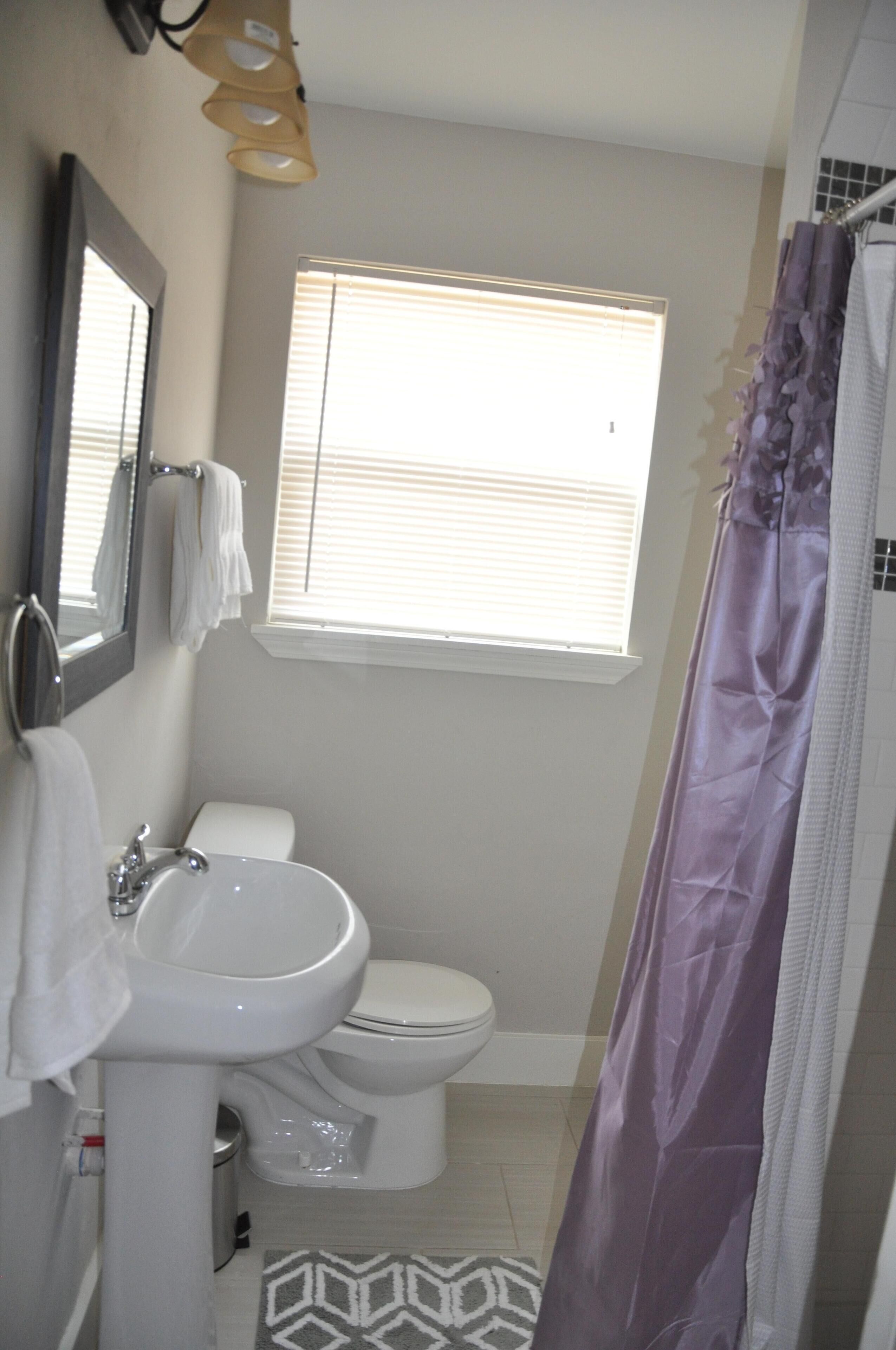Ein Badezimmer mit Waschbecken, Toilette und einem Fenster mit Jalousien.