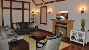 Una sala de estar con chimenea, sofá, mesa de centro y televisor.