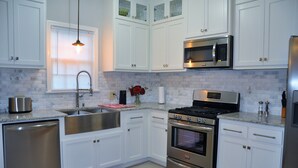Una cocina moderna con armarios blancos, electrodomésticos de acero inoxidable y un tapete rojo.