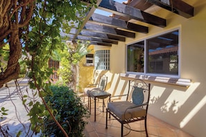 A patio with a table and chairs, a pergola, and a window overlooking a building. - Villa Agave Azul | 5BR Ocean View Villa | Pool, Jacuzzi & Golf Views (Cabo del Sol)