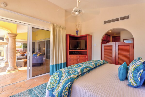 A bedroom with a bed, a TV, and a sliding glass door leading to an outdoor area.