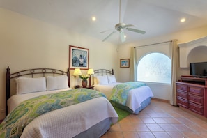 A hotel room with two beds, a ceiling fan, a TV, and a window with a view.