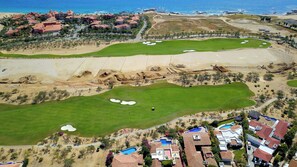 A golf course with bunkers, a swimming pool, and residential buildings.