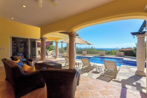 A poolside area with lounge chairs and a view of the ocean.