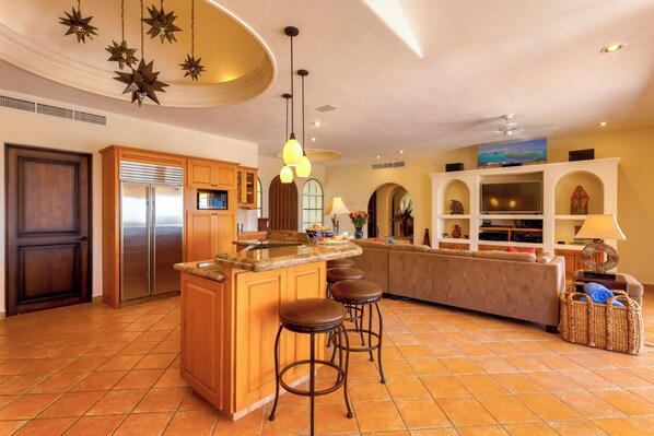A spacious kitchen with a central island, bar stools, and a dining area with a sofa.
