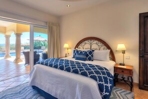 A hotel room with a large bed, two bedside lamps, a wooden headboard, a view of the pool area, and a sliding glass door.