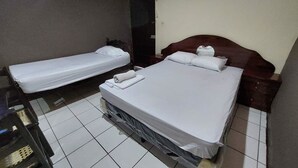 Een hotelkamer met twee eenpersoonsbedden, een houten hoofdbord en een klein nachtkastje.