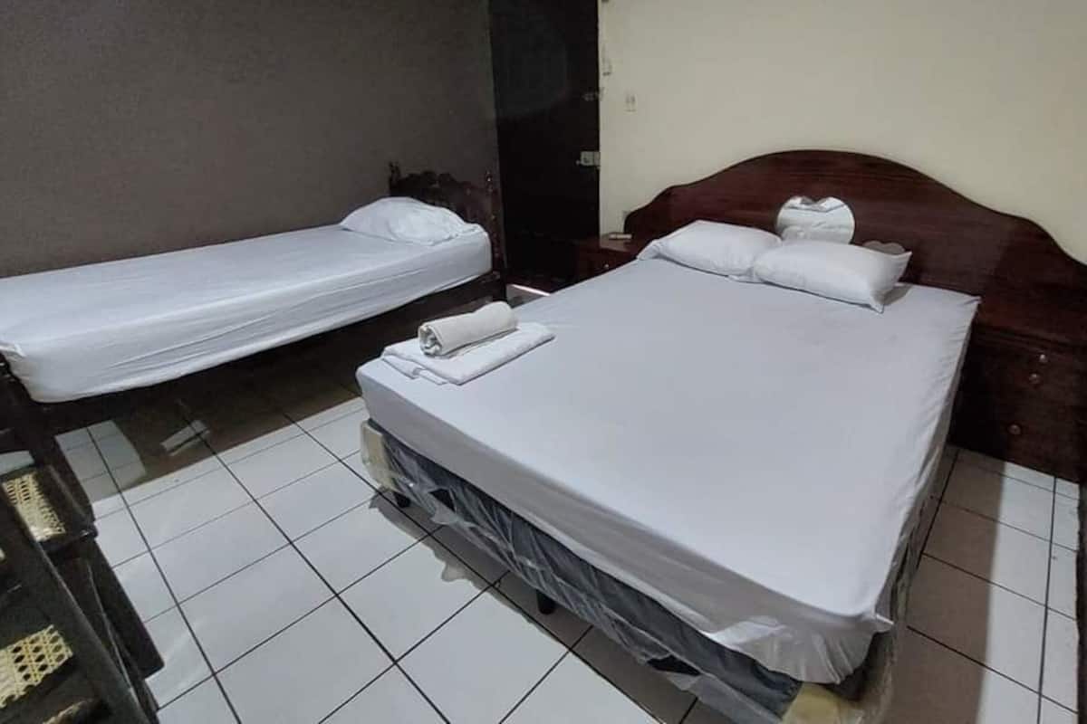 A hotel room with two single beds, a wooden headboard, and a small bedside table.